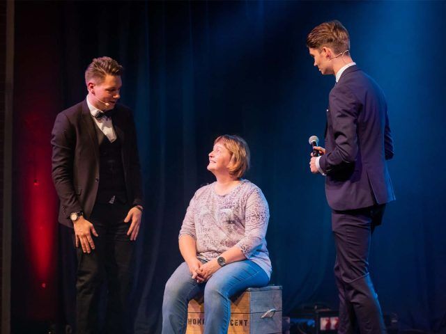 Zuschauerin sitzt auf einer Kiste, Thomas Majka und Vincent Frommer erklären die nächste Bühnenszene