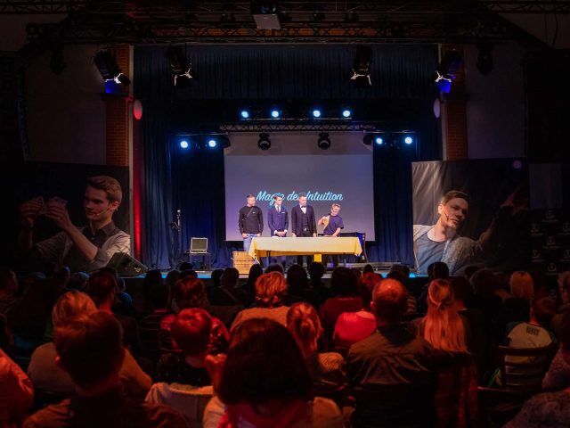 Blick aus dem Publikum auf die Bühne mit zwei Zuschauern bei der Show „Magie der Intuition“